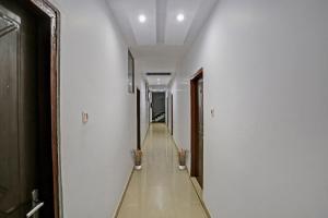 a hallway with white walls and a long hallway with two plants at Hotel O Dps Inn in Allahābād