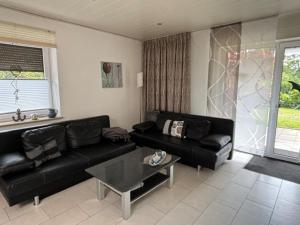 a living room with a black couch and a table at Ferienhaus 251 in Burhave in Burhave