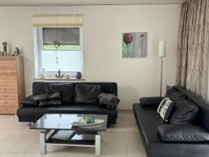 a living room with a black couch and a table at Ferienhaus 251 in Burhave in Burhave