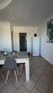 a dining room with a table and a refrigerator at Une Parenthèse à 2 in Saint-Joseph