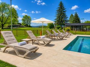a row of lounge chairs and an umbrella next to a pool at ELS OCELLS Apartaments i Cases Rurals in Camprodon