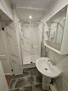 a white bathroom with a shower and a sink at The Golf Studio Woodhall Spa in Woodhall Spa +24 photos