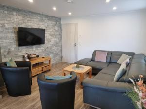 a living room with a couch and chairs and a tv at Eifel-Dream Schneifelhaus in Kobscheid