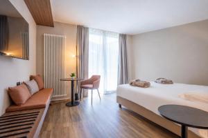 a hotel room with a bed and a table and a chair at Alchimia WellResort in Comano Terme