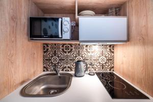 a kitchen with a sink and a microwave and a tv at Prasonisi Lighthouse Studios in Prasonisi +95 photos