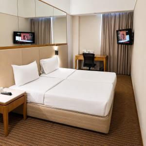 a hotel room with a white bed and a desk at Silka Maytower Kuala Lumpur in Kuala Lumpur