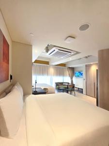 a bedroom with a large white bed and a living room at Coliwoo Midtown - CoLiving in Singapore