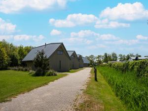 a dirt road next to a row of houses at Aan Noordzee Villa Veranda huisdier toegestaan max 2 in Sint Maartensvlotbrug