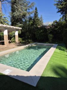 a swimming pool in a yard with a green lawn at Villa Axarquía de Gredos y Casa Paco de Gredos in Arenas de San Pedro