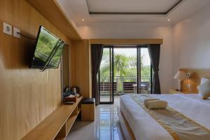 a bedroom with a bed and a tv on a wall at Kelingking Sunset Point Hotel in Nusa Penida