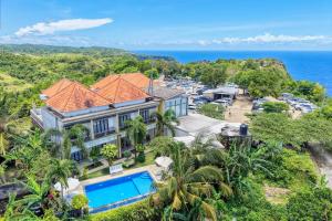 an aerial view of a house with a swimming pool and the ocean at Kelingking Sunset Point Hotel in Nusa Penida