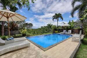 an image of a swimming pool with chairs and an umbrella at Kelingking Sunset Point Hotel in Nusa Penida