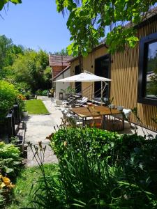 an outdoor patio with tables and an umbrella at Le 10, Reflets dans l'Eau in Saint-Clair-de-la-Tour