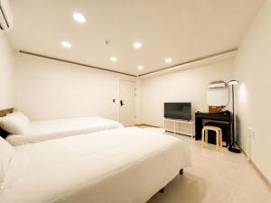 a white bedroom with two beds and a television at 아문 스테이 in Busan +64 photos