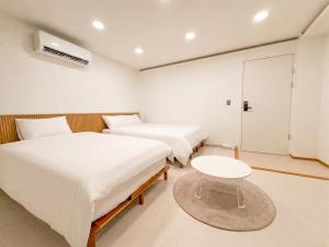 a room with two beds and a table in it at 아문 스테이 in Busan