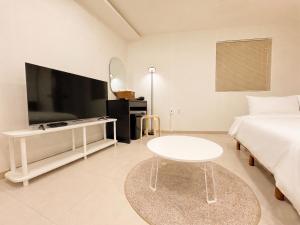 a white room with a bed and a table and a tv at 아문 스테이 in Busan