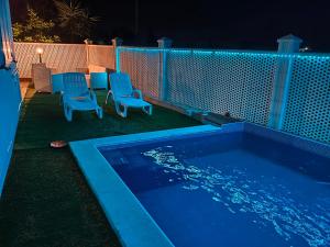 a swimming pool with two blue chairs next to a fence at DolceApulia Country House in Conversano +31 photos