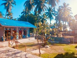 a house with a blue roof and palm trees at Tirosa in Nembrala