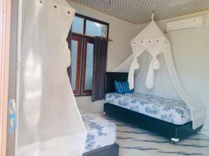 a bedroom with two beds with mosquito nets at Tirosa in Nembrala