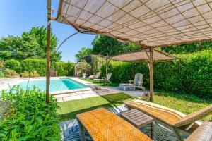 a backyard with a pool with chairs and an umbrella at Chambres D'hôtes Les Seignerolles in Pernes-les-Fontaines