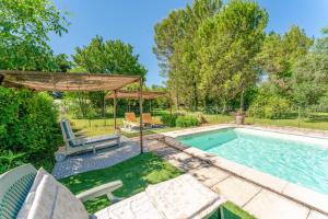 a backyard with a swimming pool and a umbrella at Chambres D'hôtes Les Seignerolles in Pernes-les-Fontaines