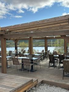 a wooden deck with tables and chairs and a lake at Skoogs Logi Lägenheter in Funäsdalen