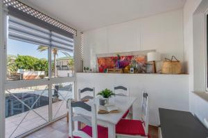 a white kitchen with a table and chairs and a balcony at Piccola Oasi Corralejo in Corralejo