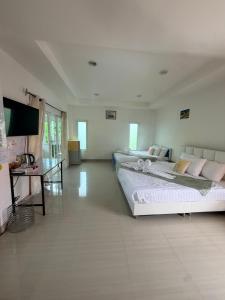 a large bedroom with two beds and a desk at Home Hakim in Cha Am