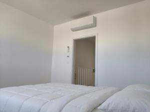 a white bedroom with a white bed and a window at Villa La Pollo in Senec