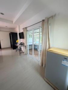 a living room with a refrigerator and a table at Home Hakim in Cha Am