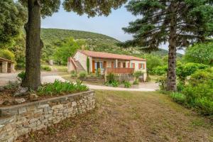 a house with a stone wall and trees at Gîte La Motette Drôme Provençale in Rousset-les-Vignes