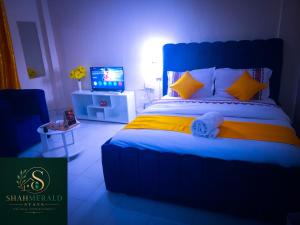a bedroom with a blue and yellow bed and a television at SHAHMERALD Stays Studio in Kakamega