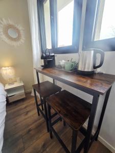 a wooden table in a room with two windows at Chambre Premium "Plume"- SDB privée & coin repas in Sainte-Geneviève-des-Bois