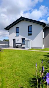 a white house with a yard with purple flowers at Ferienwohnung Am Kleinen Haff in Garz
