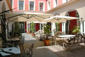 a patio with tables and chairs and umbrellas at Hôtel De Paris in Sète