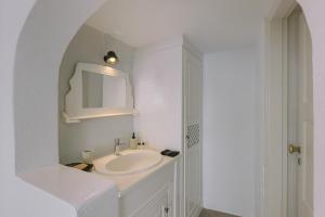 a white bathroom with a sink and a mirror at Afroessa Hotel by Caldera Houses in Imerovigli