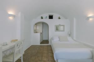 a white room with two beds and a table at Afroessa Hotel by Caldera Houses in Imerovigli