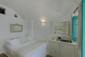 a white bedroom with a bed and a sink at Afroessa Hotel by Caldera Houses in Imerovigli