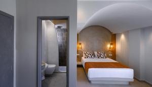 a hotel room with a bed and a bathroom at Anemone Luxury Suites in Fira