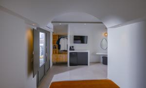 a white bathroom with a sink and a mirror at Anemone Luxury Suites in Fira