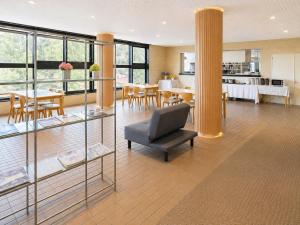 a living room with a chair and tables and windows at Zao Sunvalley Hotel in Yamagata