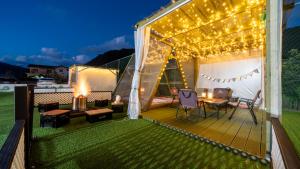 a deck with a table and chairs and lights at Gapyeong Dangdangi Pet Pension Green in Gapyeong
