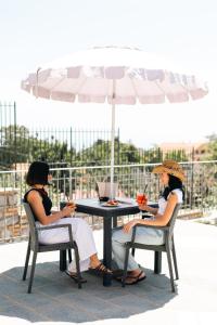 two women sitting at a table under an umbrella at The Chalet, guest house in Agerola