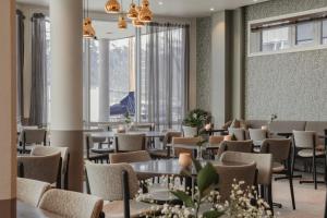 a dining room with tables and chairs and windows at Home Hotel Aurora in Tromsø