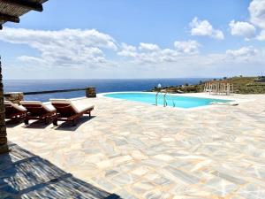 a swimming pool with chairs and a view of the ocean at Koundouros 186 View in Koundouros
