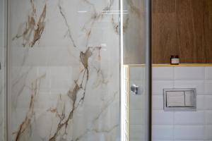 a bathroom with a shower with white marble walls at Aparthotel Cieplice in Jelenia Góra