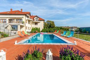 a swimming pool with chairs and a house at Hotel nad morzem - Art-Pension - Dąbrowa - Holiday & SPA in Świerzno