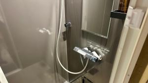 a shower with a hose attached to a glass wall at MAGATAMA.INN in Sumoto