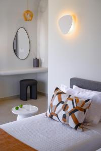 a bedroom with a bed with a mirror and a table at Anemone Luxury Suites in Fira