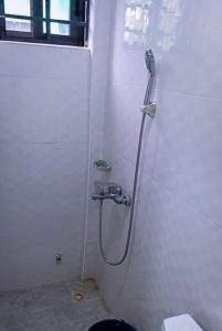 a shower in a white bathroom with a toilet at Wisny Guest House in Kasoa